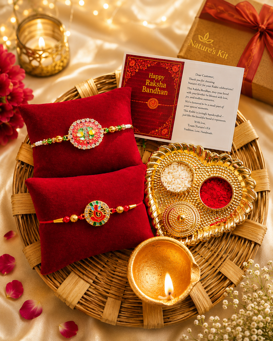 A festive Rakhi gift set arranged on a woven tray with red velvet pillowcases, two decorated Rakhi bracelets, a gold-toned diya, a heart-shaped plate with red and white powders, a card, and a Nature's Kit box on a satin background.